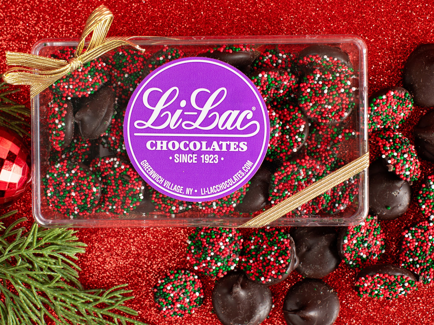 Chocolate nonpareils with red, green and white nonpareil seeds are inside a clear box.