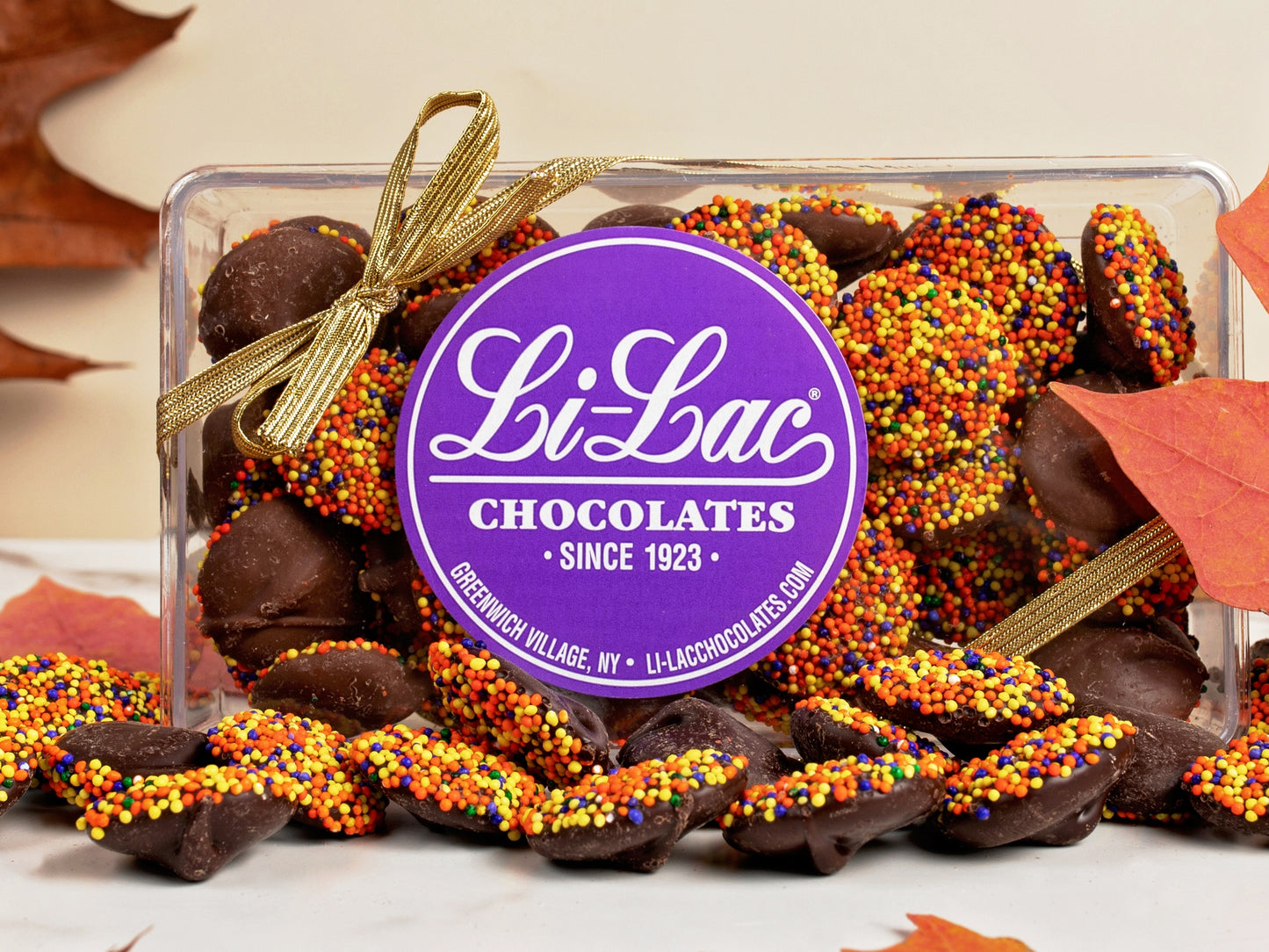 Thanksgiving colored Nonpareils in a clear box with a Li-Lac Chocolate round sticker on the lid.