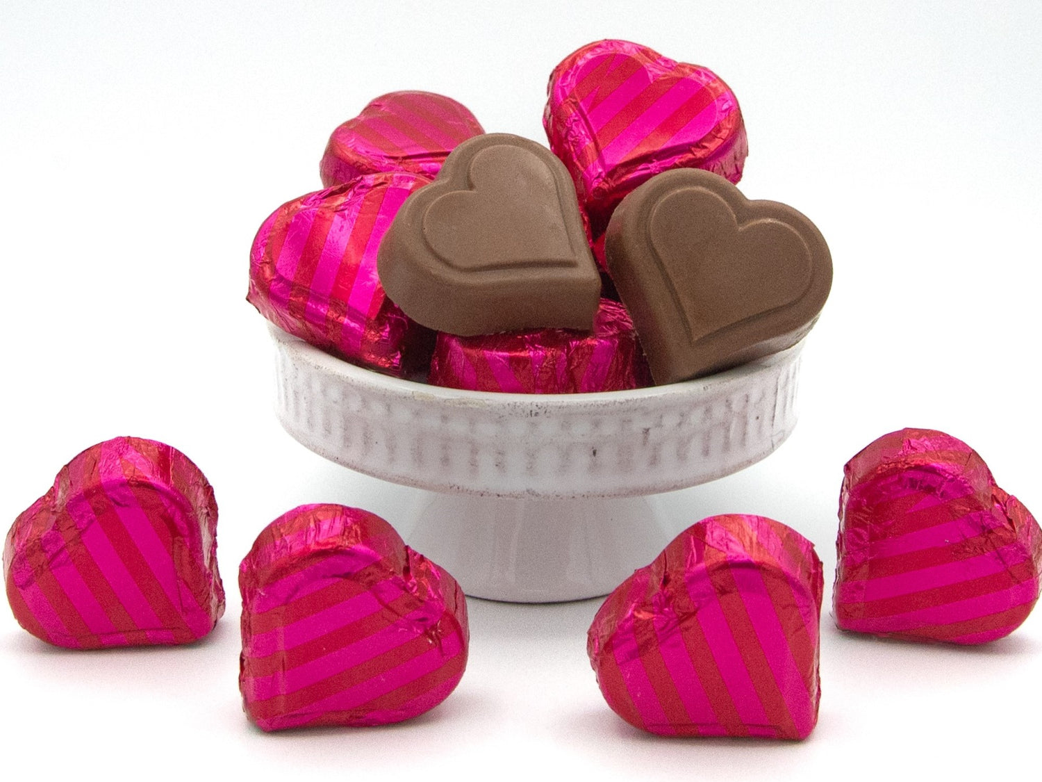 Molded chocolate hearts are wrapped in bright pink and red striped foil.