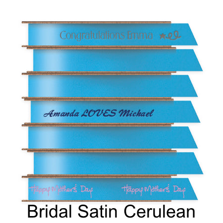 A stack of seven spools of shiny cerulean satin ribbon with custom messages printed on them in different colors.