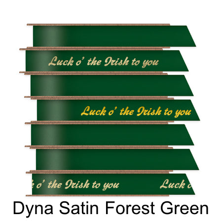 A stack of seven spools of shiny forest green satin ribbon with custom messages printed on them in different colors.