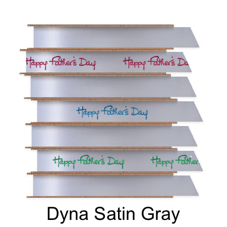 A stack of seven spools of shiny soft gray satin ribbon with custom messages printed on them in different colors.