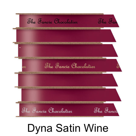 A stack of seven spools of shiny wine satin ribbon with custom messages printed on them in different colors.