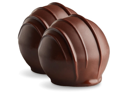 Two amaretto truffles sit side by side. They are enrobed in dark chocolate with dark chocolate drizzles in straight lines on top.