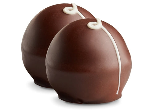 Two brandy truffles sit side by side. They are enrobed in dark chocolate with a white chocolate drizzle in a swirl pattern on top.