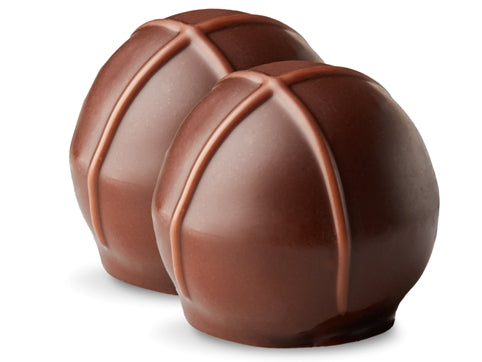 Two dulce de leche truffles sit side by side. They are enrobed in dark chocolate with milk chocolate drizzles in an X pattern on top.
