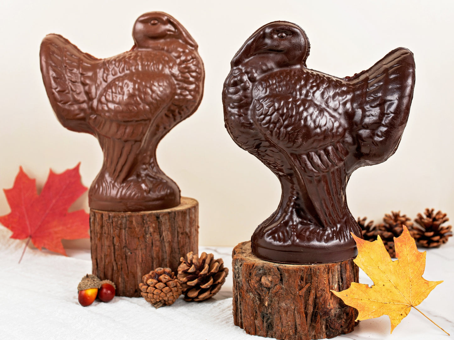 Two chocolate turkeys standing proud on a slice of a tree branch