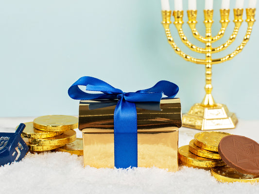 A small gold chest with a blue ribbon tied around it, and other Chanukah decorations on the snow.