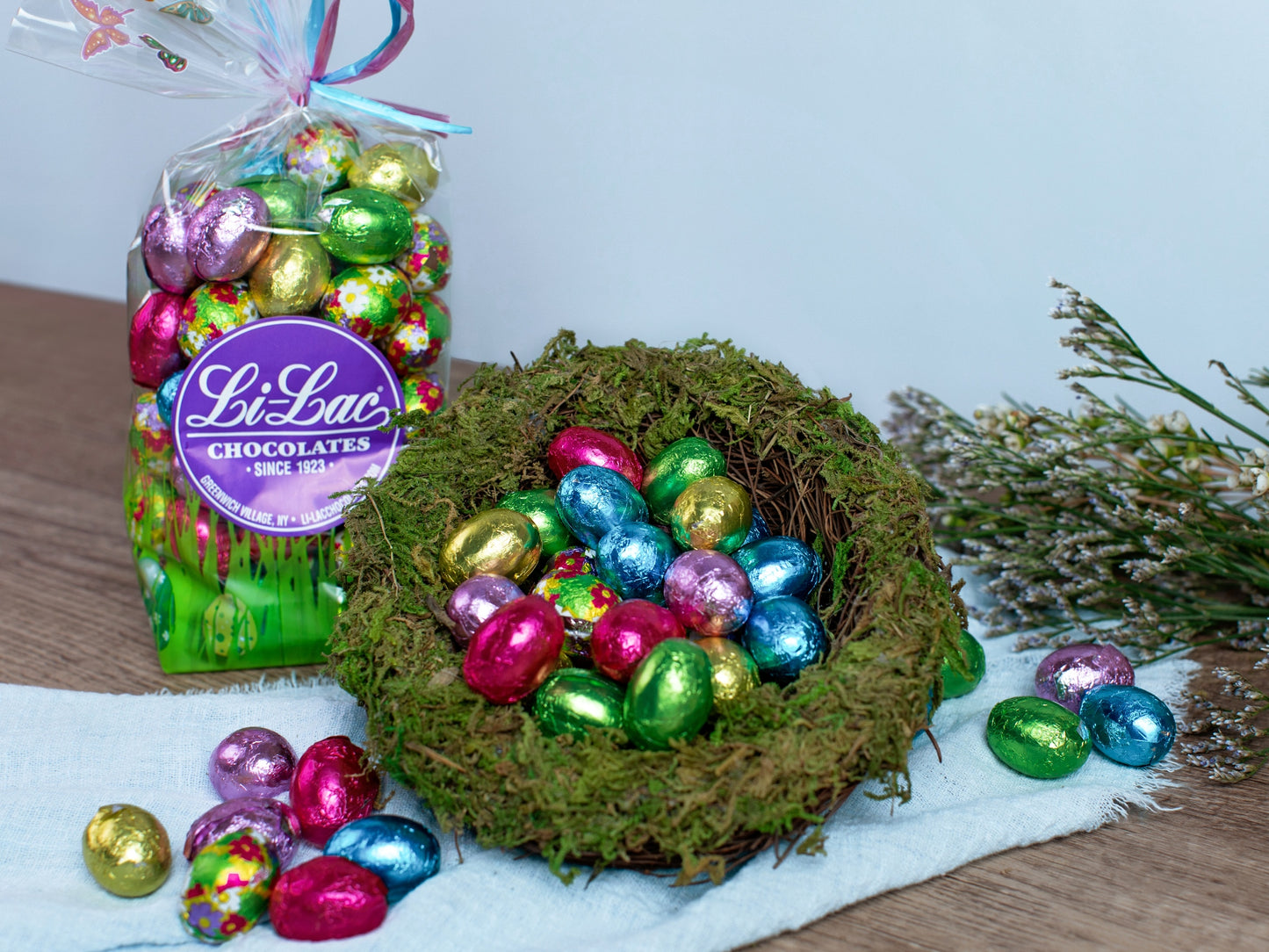 colorful chocolate eggs artfully arranged in a next with a bag of chocolate eggs behind it.