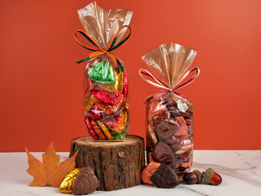 Two clear bags filled with chocolate foiled leaves on a white marble table