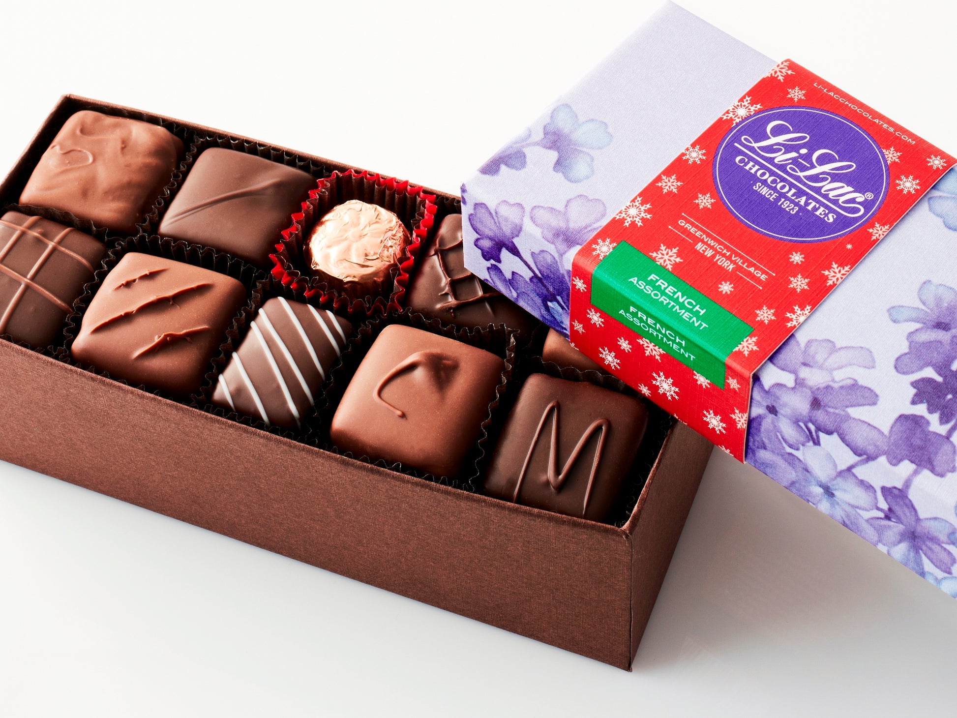 An open box showing the chocolate pieces with a red starry holiday sleeve on the box top