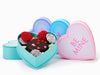 Four colorful heart shaped boxes artfully arranged and filled with Valentine Oreos, Nonpareils, and Conversation hearts.