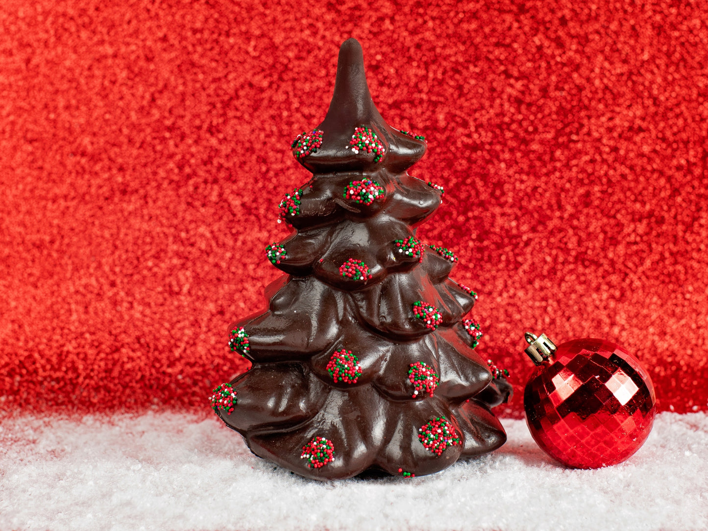 A large chocolate molded evergreen tree with nonpareil seeds on the tree boughs in red and green.