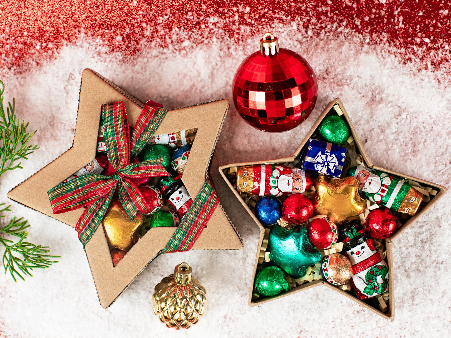 A star shaped box made out of brown kraft paper has brightly colored foil wrapped chocolates inside. 