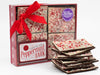 A Box filled with Chocolate Peppermint Bark and a small stack of bark in front of the box.