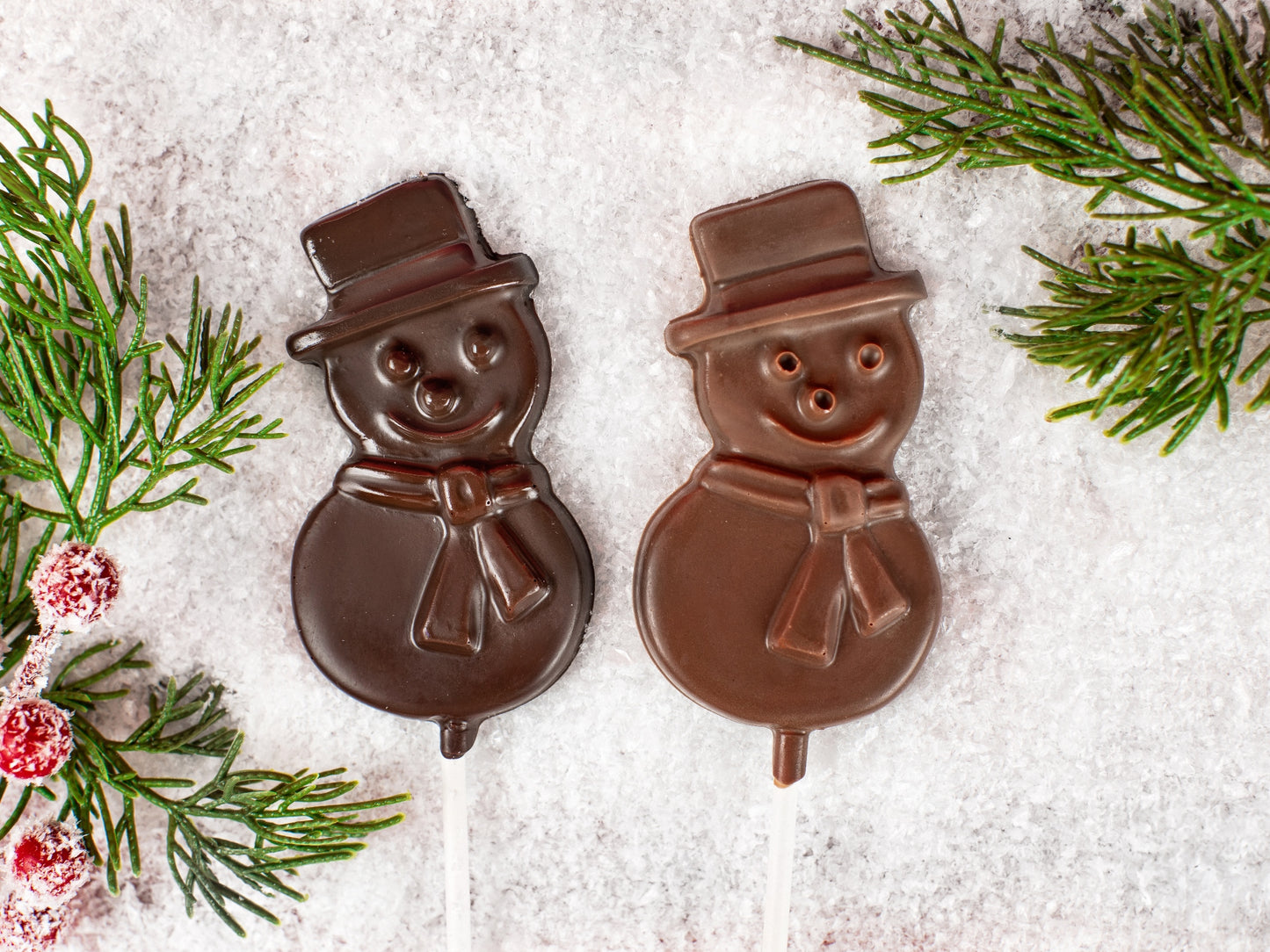 Two molded chocolate snowman pops on a stick.