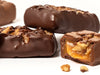 Milk and dark chocolate Walnut Caramel bars stacked with one bar cut open to reveal the caramel inside.