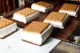 Marshmallow S'Mores bars running down the enrober being covered with chocolate.