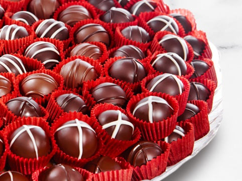 Two layers of beautiful assorted truffles sit, stacked in two layers on a serving tray.