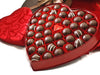 Forty-one assorted chocolates sit inside a heart shaped box. The square, outer box stands nearby.