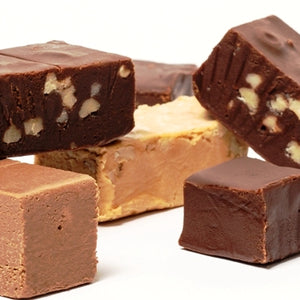 Bars of chocolate, chocolate walnut, peanut butter and maple walnut fudge are stacked together. 